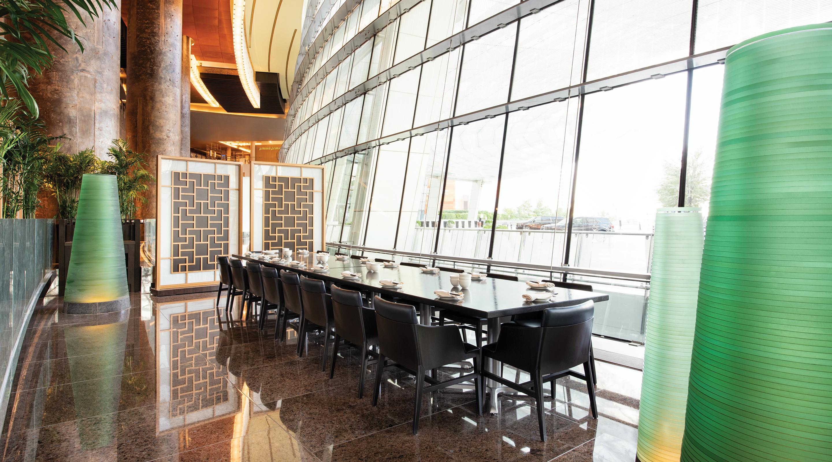 A private dining room with a long table next to floor to ceiling windows.